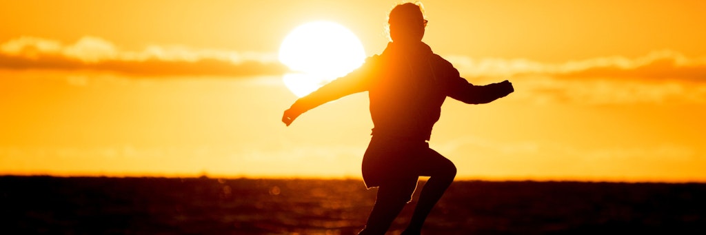 Ein Mädchen springt vor der untergehenden Sonne am Nordstrand im Sand. Die Pandemie hat die Lebenszufriedenheit vieler Menschen in Deutschland einer Umfrage zufolge in einigen Bereichen auch verbessert. 