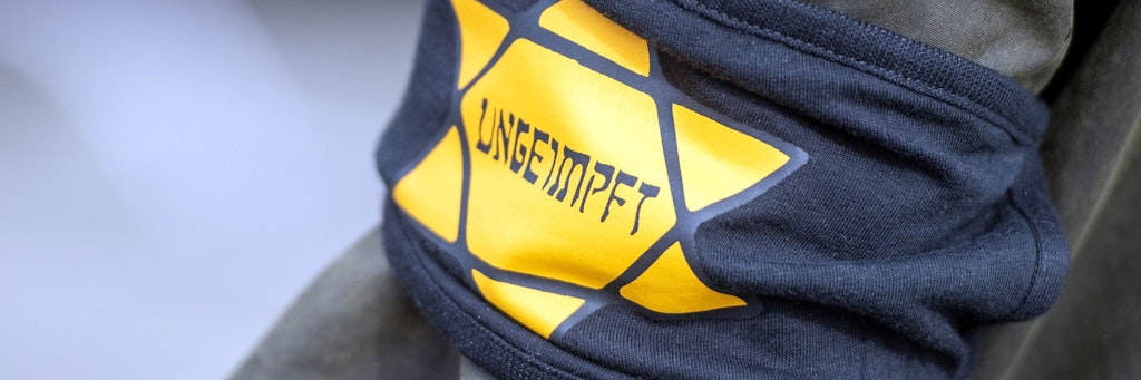 Bei einer Coronaleugner-Demo trägt ein Teilnehmer eine Armbinde mit einem gelben Stern, der an einen Judenstern erinnern soll.