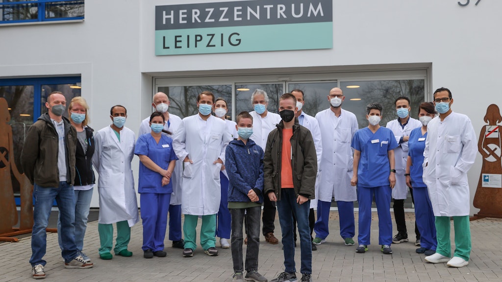 Die Zwillinge Jamie (l.) und Kilian sowie das Team der Kinderherzchirurgie stehen vor dem Herzzentrum Leipzig.