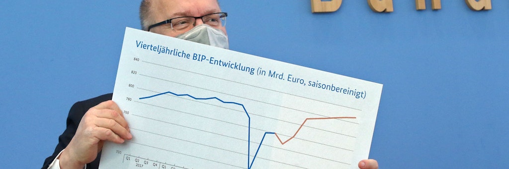 Peter Altmaier (CDU) mit einer Grafik, die die erwartete Entwicklung der Wirtschaft zeigt: 2020 steil abwärts und wieder hoch, rot dargestellt ist die Prognose. 