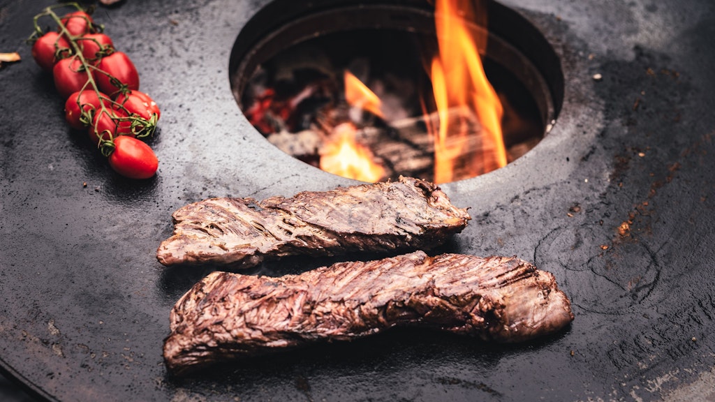 Die Feuerplatte - hier mit Rispentomaten und Nierenzapfen - gibt es als gusseisernen Aufsatz für den Kugelgrill. 