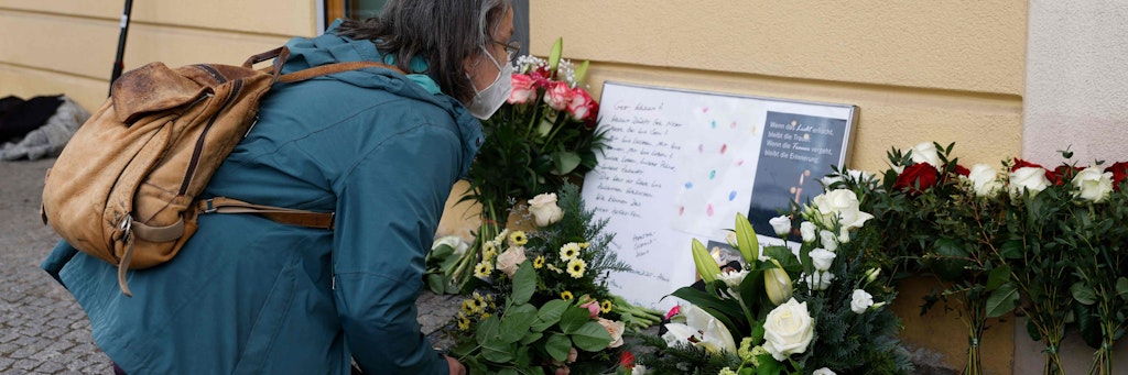 Eine Potsdamerin legt vor dem Oberlin-Wohnheim Blumen für die vier getöteten Bewohner ab. 
