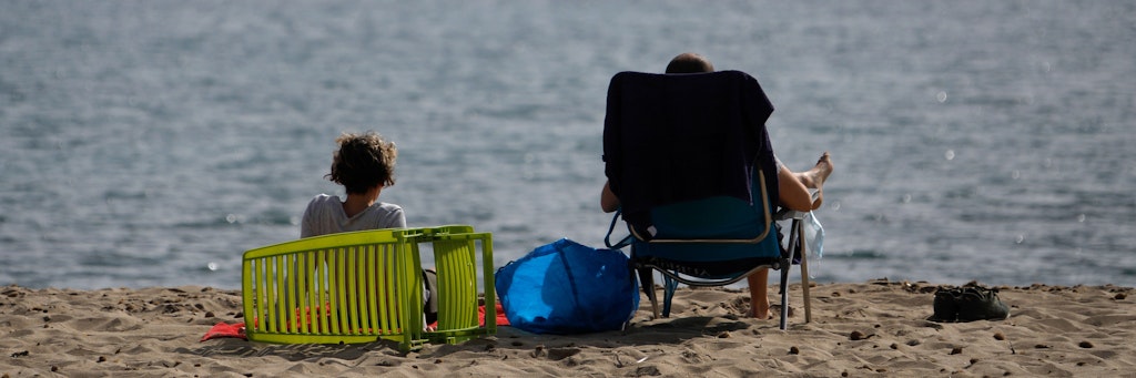 Menschen sonnen sich am Strand von Pollença auf Mallorca. 