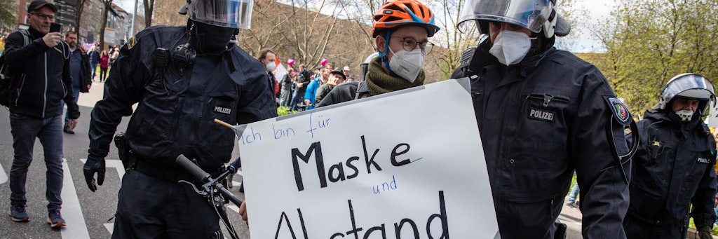 Ein Gegendemonstrant fordert "Maske und Abstand", wird von Polizisten abgeführt, damit die "Querdenken"-Demo freien ´Durchmarsch hat.