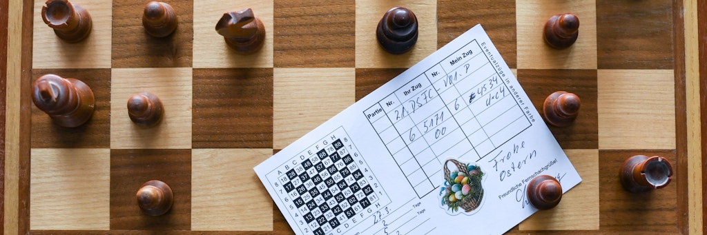 In der Wohnung von Schachspieler Heiermann, der Fernschach per Post spielt, liegt auf einem Schachbrett mit den Schachfiguren eine Postkarte, die den Zug des anderen Spielers übermittelt. Beim Fernschach mittels Postkarte oder Brief werden die jeweiligen Züge aufgeschrieben, in einer Kladde dokumentiert und dann per Post an den anderen Spieler übermittelt.