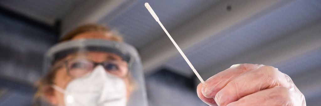 Eine Helferin hält einen Teststab bei einem Schnelltest auf das Coronavirus. 