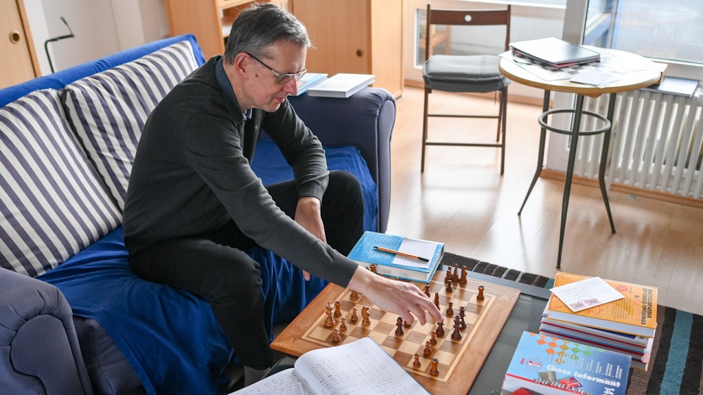 Der Schachspieler Ludger Heiermann spielt in seiner Wohnung Fernschach per Post und ist von seinen Aufzeichnungen und Schachbüchern umgeben.