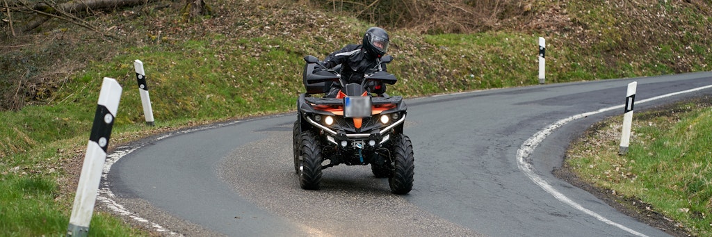 Ein Quadfahrer ist auf einer Landstrasse unterwegs. 