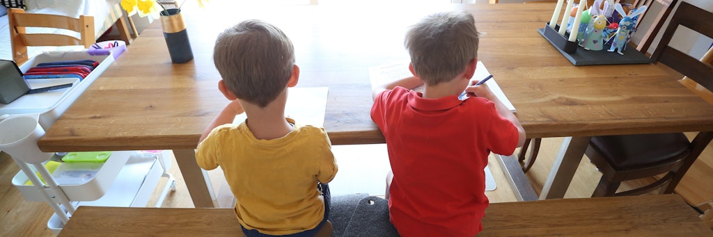 Zwei Jungen füllen zu Hause Lernbücher aus. Seit Beginn der Corona-Pandemie sitzen Geschwister enger aufeinander als je zuvor. 
