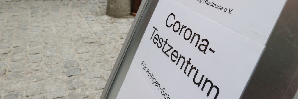 Ein Hinweisschild zum Corona Schnelltest steht vor dem DRK Centrum in der Innenstadt.