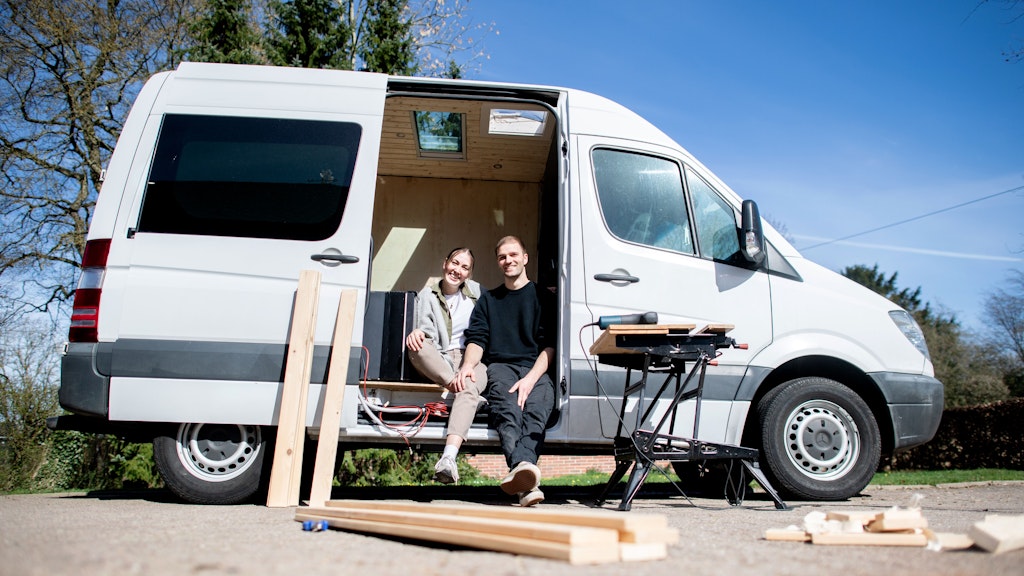 Greta Thomas und Hannes Wehrmann sitzen in ihrem Mercedes-Benz Sprinter, den das Paar in Eigenarbeit zu einem Campervan umbaut. 