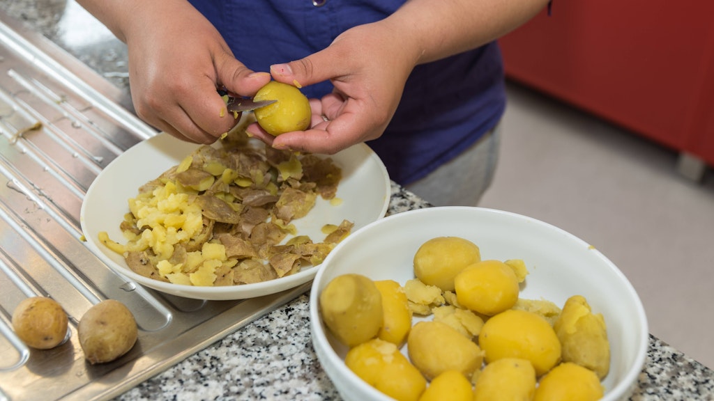 Als Grundlage für den warmen Kartoffelsalat mit Speck und Bohnen dienen Pellkartoffeln.