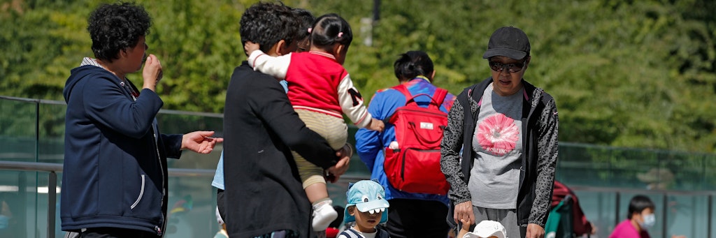 Anwohner in Peking bringen ihre Kinder zum Spielen auf ein Gelände in der Nähe eines kommerziellen Bürogebäudes. 