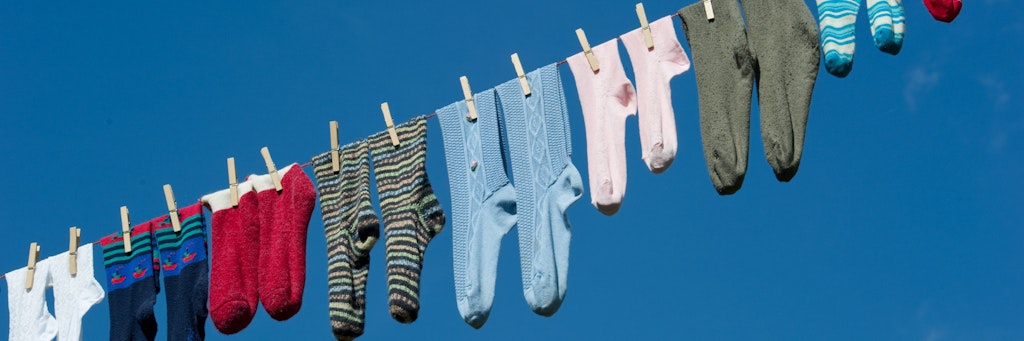 Noch fröhlich vereint: Paarweise hängen diese Socken auf der Leine – ein Wäschesack kann sie vor dem Verschwinden in der Waschmaschine bewahren, andernfalls droht ewige Socken-Vereinzelung.