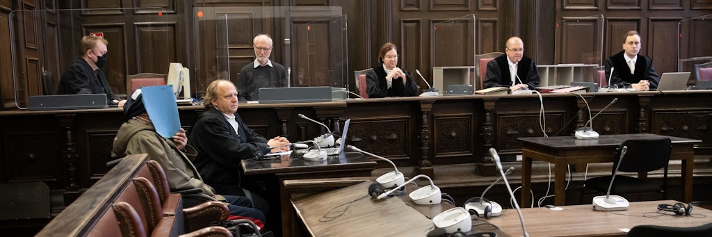 Der Angeklagte verdeckt in diesem Bild vom Prozessbeginn im November sein Gesicht.