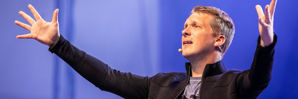 Oliver Pocher zeigt auf einer Bühne große Gesten.