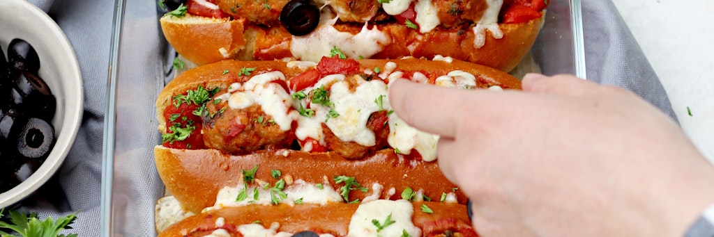 Bevor die Meatball-Sandwiches im Ofen für 10 Minuten mit Mozzarella überbacken werden, kommen in jedes Briochebrötchen Hackbällchen und etwas Soße. 