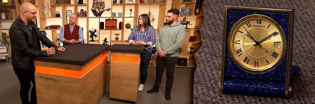 Dieser kleine Wecker kam bei „Bares für Rares“ unter den Hammer. Links: Experte Sven Deutschmanek, Moderator Horst Lichter und die Kandidaten im Studio.