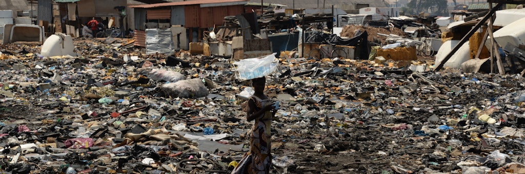 Eine Frau steht auf der Freifläche hinter dem Schrottplatz von Agbogbloshie (Ghana).