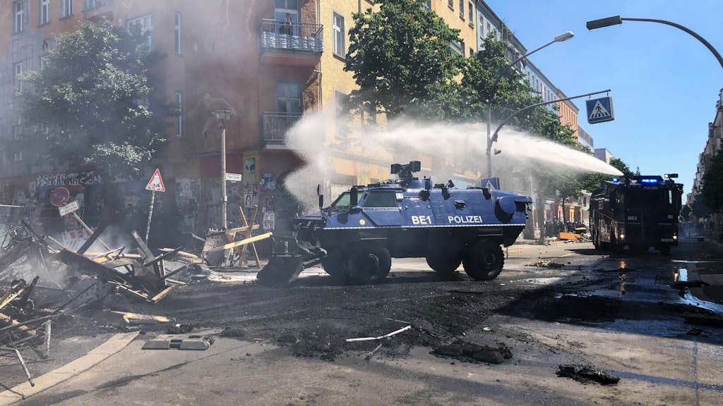 Ein Räumpanzer der Polizei schiebt in der Rigaer Straße eine Barrikade beiseite, dahinter ist ein Wasserwerfer im Einsatz.