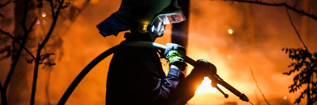 Ein Feuerwehrmann bekämpft mit einem Wasserstrahl einen Waldbrand bei Ziltendorf.