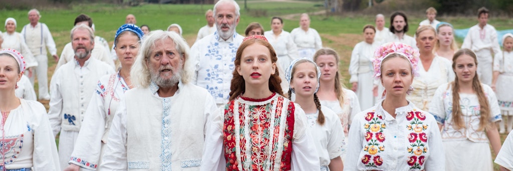 Gerade bei den nettesten Menschen können üble Abgründe lauern … Maja (Isabelle Grill) im Film „Midsommar“ mit Dorfbewohnern in traditionell schwedischer Kleidung.