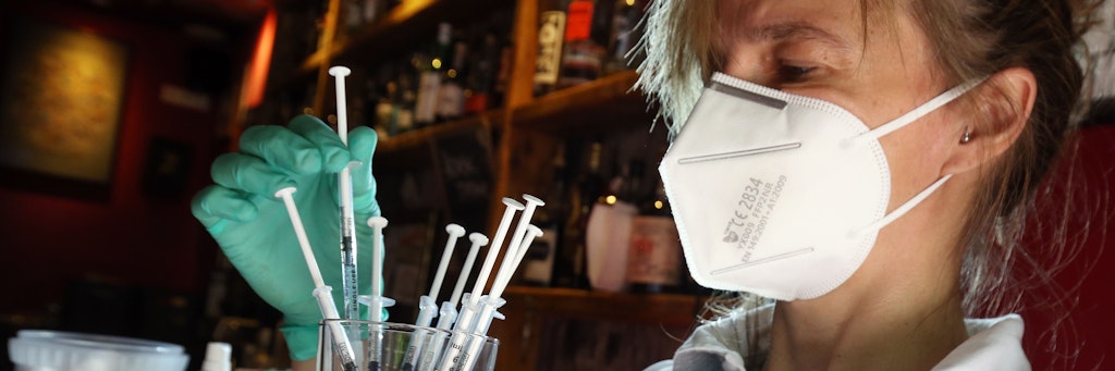 Eine medizinische Fachangestellte sortiert in der Revolte-Bar im Berliner Bezirk Friedrichshain Spritzen mit dem Impfstoff Johnson & Johnson in einem Glas. 