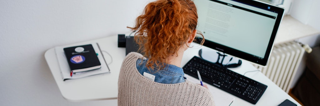Eine Frau arbeitet in ihrer Wohnung vor einem Computer im Homeoffice.