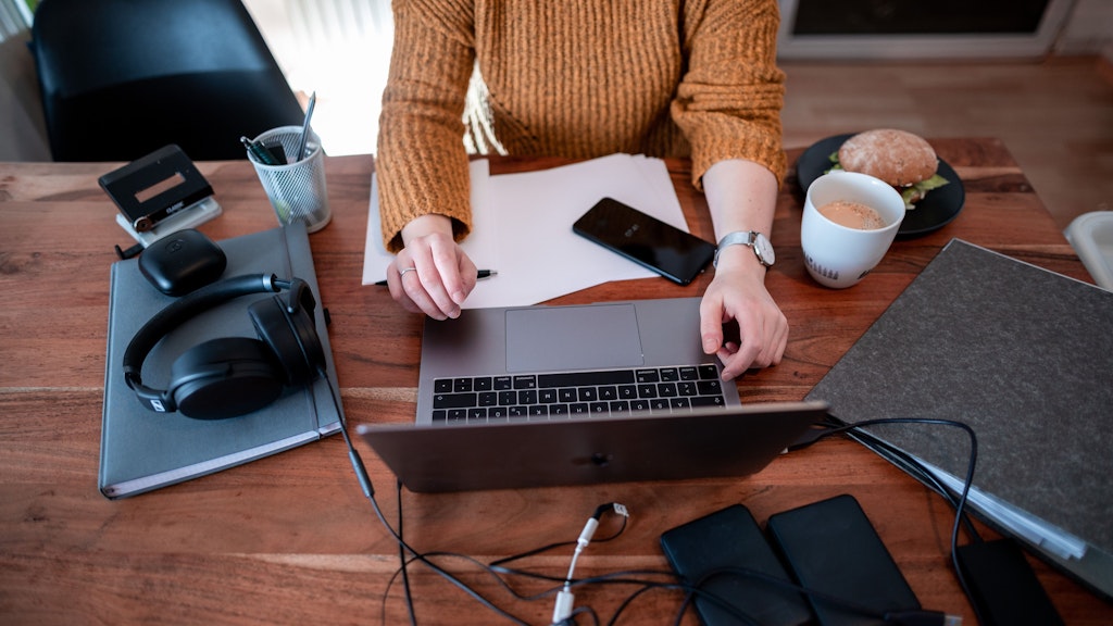Eine Frau sitzt mit einem Laptop an einem Tisch im Homeoffice - wer zu Hause technisch gut ausgestattet ist, kann meist auch problemlos seine Arbeit dort erledigen. 