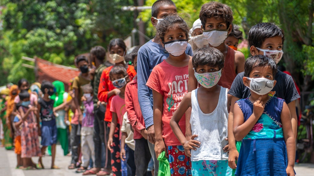 Indische Kinder warten in einer Schlange in Neu Delhi auf Essen.