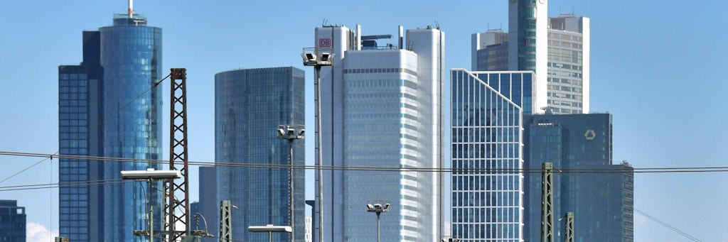 Skyline in Frankfurt. In der Innenstadt ist ein Mann auf ein Hochhaus gekraxelt.