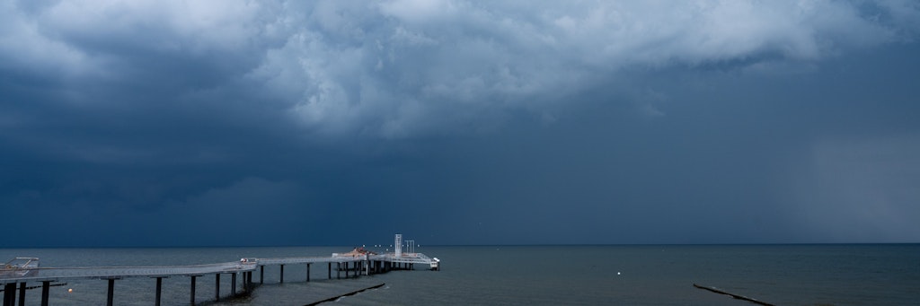 Über den Strandkörben am Strand der Insel Usedom ziehen dunkle Regenwolken auf. 