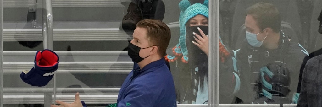 Seattle-Kraken-Fan Nadia Popovici steht am Spielfeldrand hinter Brian „Red“ Hamilton, Zeugwart der Erstliga-Eishockey-Mannschaft Vancouver Canucks.