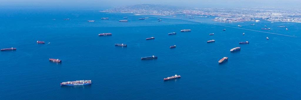 Containerschiffe liegen vor den Häfen von Los Angeles und Long Beach auf Reede, häufig tagelang, und warten auf Entladung. 
