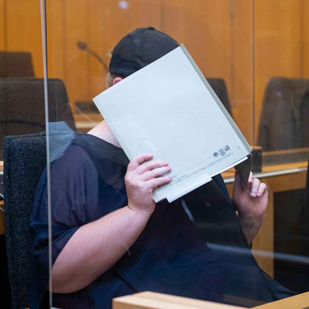 Zu Beginn des Prozesses im Missbrauchskomplex Münster sitzt die Mutter eines Opfers im Landgericht Münster und verdeckt ihr Gesicht mit einer Mappe. Die Anklage wirft der 31-Jährigen vor, den schweren sexuellen Missbrauch ihres heute elfjährigen Sohnes durch ihren Lebensgefährten nicht verhindert zu haben, obwohl sie davon wusste.