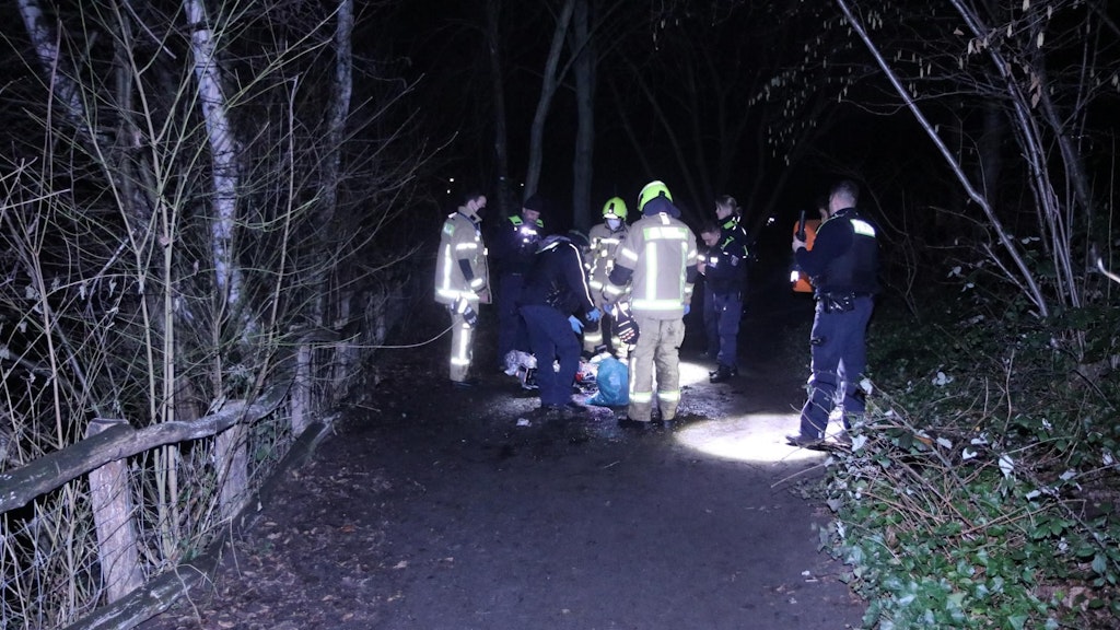 Beamten durchsuchen am Unfallort die Sachen des Flüchtigen, der zuvor aus einem eiskalten Teich gerettet wurde.