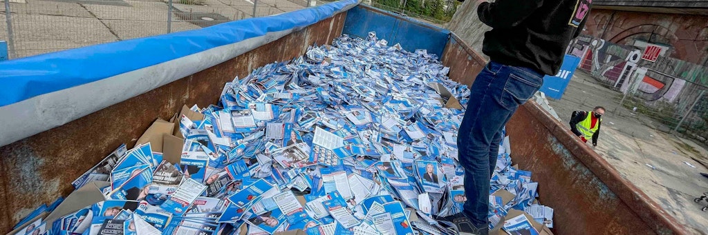Hunderttausende AfD-Flyer liegen in einem Müll-Container.