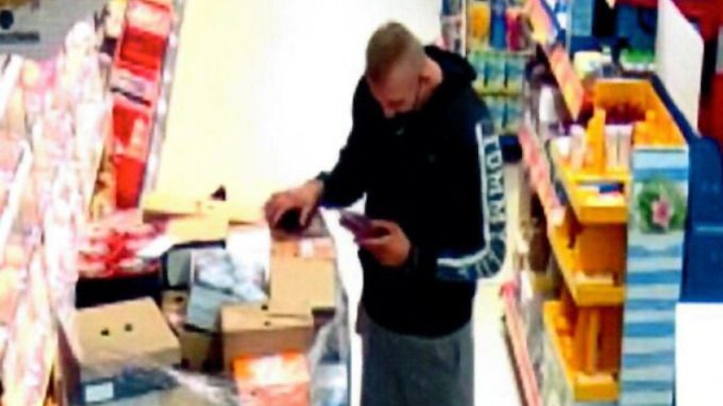 Der unbekannte Mann steckt das Inventurgerät ein.