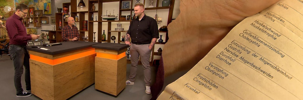 Bei der Expertise las „Bares für Rares“-Experte Detlef Kümmel auch aus der Bedienungsanleitung vor. An seiner Seite: Moderator Horst Lichter und „Bares für Rares“-Kandidat Jonas Leßmann.