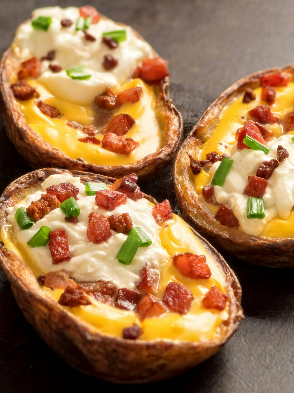 Die Kartoffeln werden mit geriebenem Käse und Schinken gefüllt und anschließend überbacken.