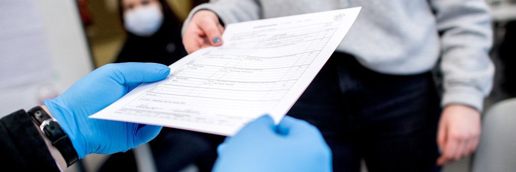 Ein Lehrer verteilt Halbjahreszeugnisse an Schülerinnen und Schüler.