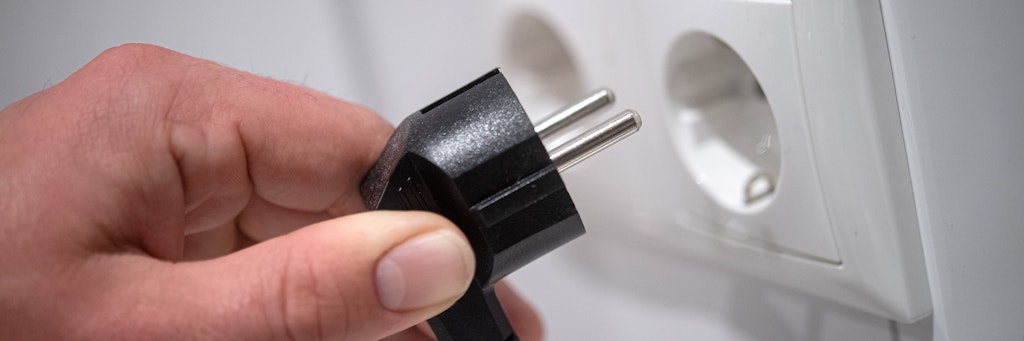 Ein Stecker wird in eine Steckdose gesteckt.