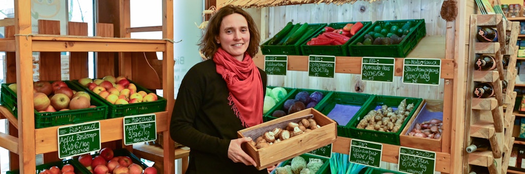 Helene Berthelot, Chefin vom Bioladen Calendula, steht zwischen den Regalen und räumt frisches Obst und Gemüse ein.