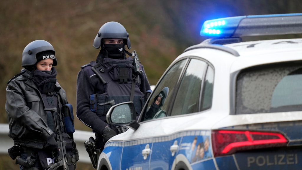Polizisten sichern eine Straßensperre in der Nähe des Tatortes.