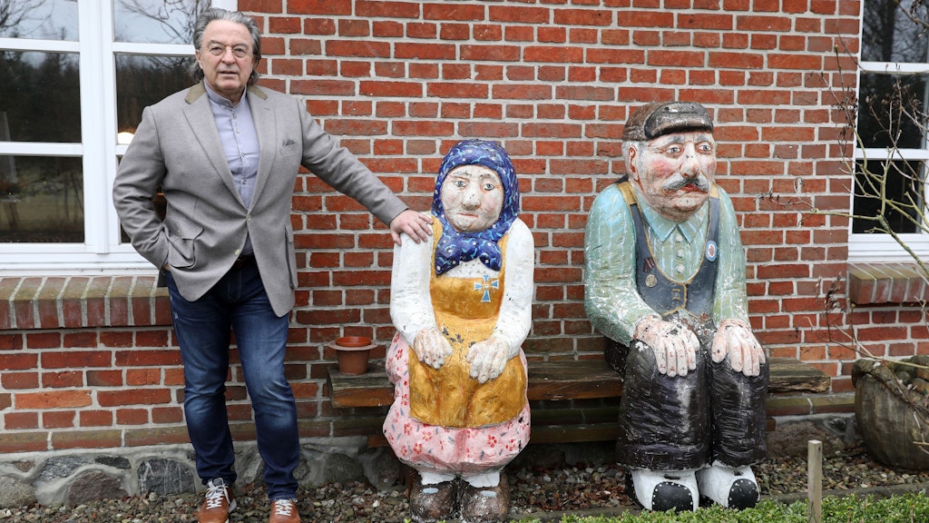 Peter-Michael Diestel, steht vor seiner Kanzlei neben einer Skulptur von Holzbildhauer Günter Schumann.