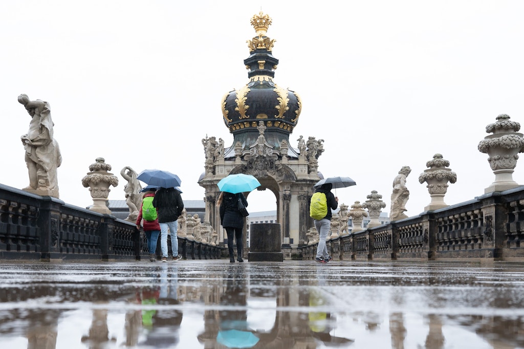 Passanten spazieren im Regen vor dem Kronentor im Zwinger entlang.