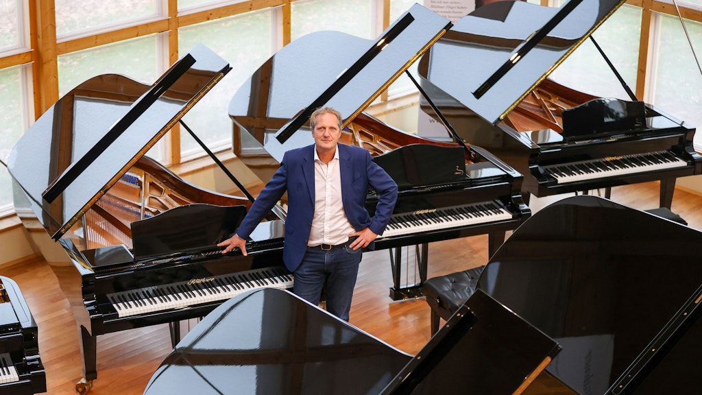 Christian Blüthner, Geschäftsführer der Blüthner Pianofortefabrik, steht zwischen den Instrumenten im Klaviersalon des Unternehmens.