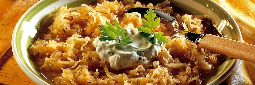 Sauerkrautsuppe ist ein deftiges Gericht, das einfach schmeckt. Am besten wird der Eintopf mit einem Klecks Schmand serviert.