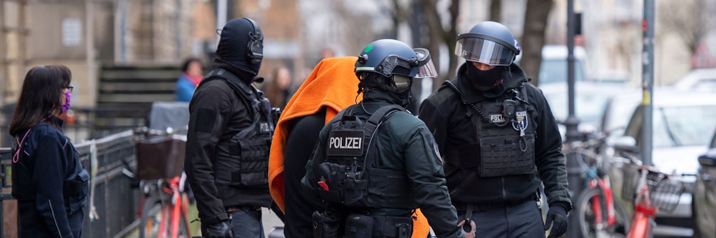 Nach der Verlesung der Anklage im Prozesses wegen Vorbereitung einer schweren staatsgefährdenden Gewalttat und Terrorfinanzierung bringen Polizisten den Angeklagten unter einer Decke aus dem Gerichtsgebäude.