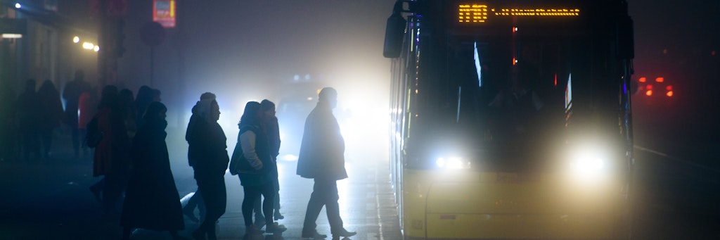 Menschen steigen während neblig-trübem Wetter in Berlin an einer Tram-Haltestelle in eine Straßenbahn (Symbolbild).
